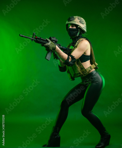 woman in military uniform with an American automatic rifle in a helmet and Balaclava on a green background