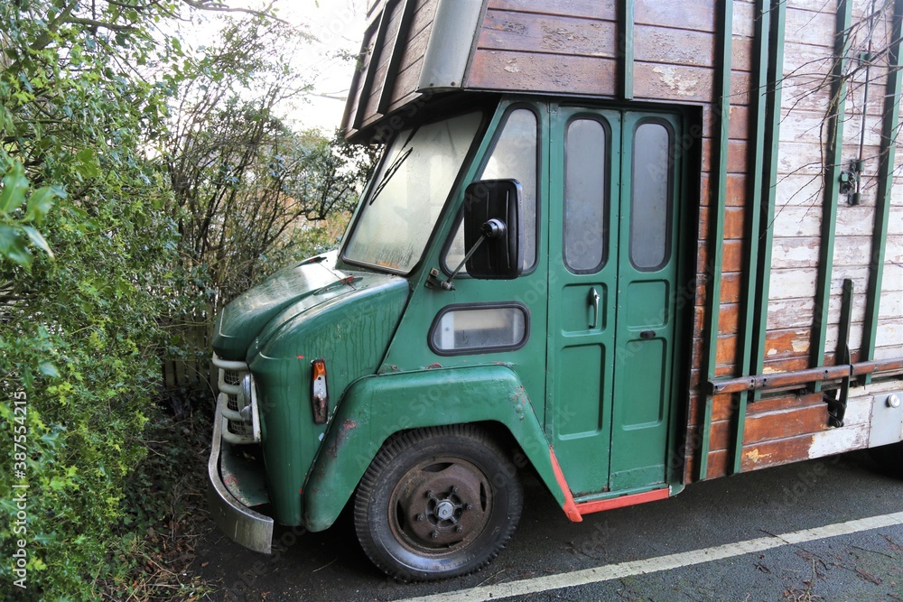 An old, green, vintage, wooden horse lorry in a car park, Gwynedd, Wales, UK.