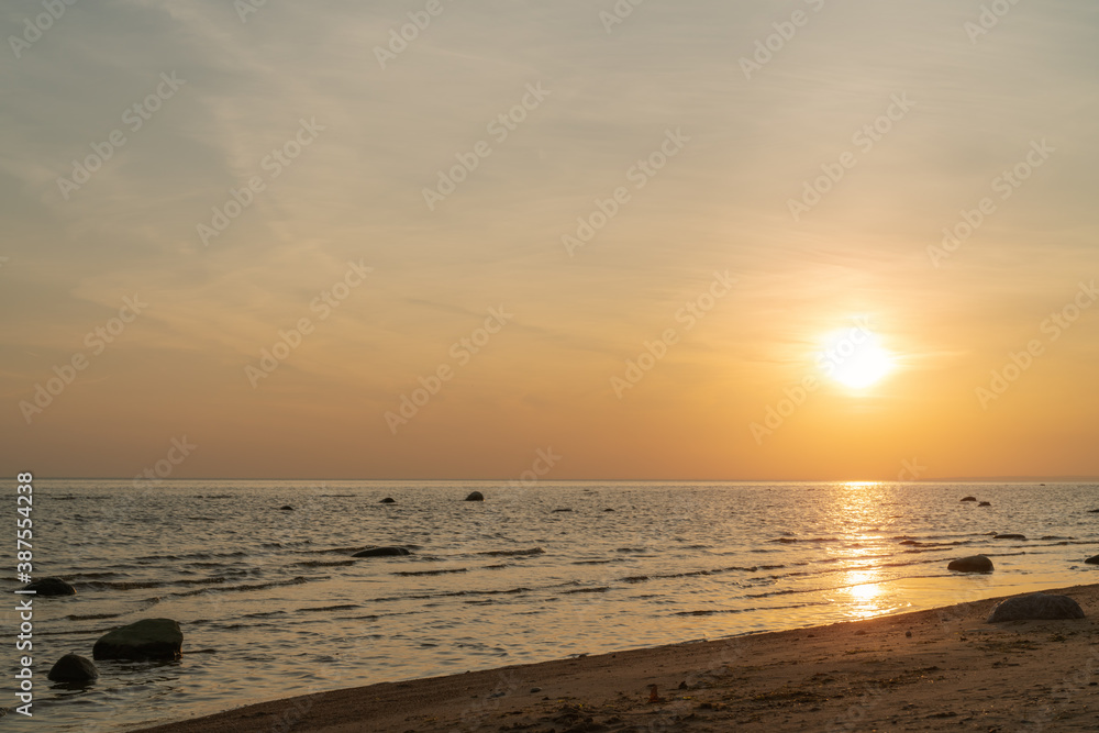 Sunset on baltic sea beach with rocks in sand