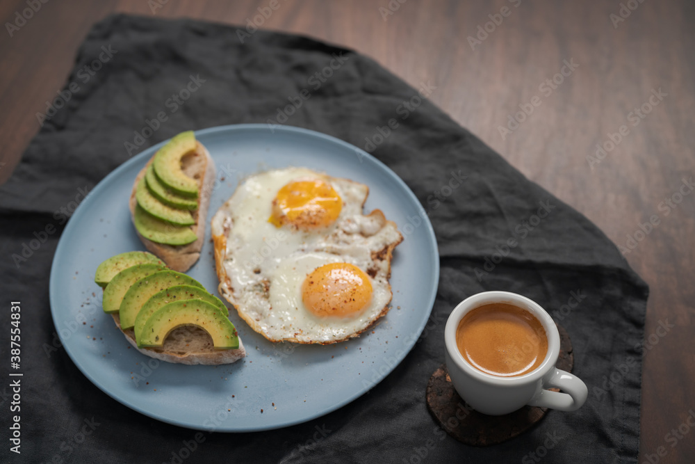 fried egg with two avocado sandwiches and espresso for breakfast on a blue plate fried egg with two avocado sandwiches and espresso for breakfast on a blue plate