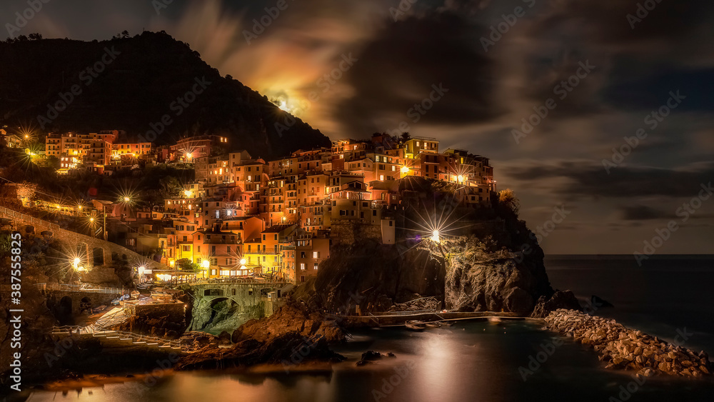 A long exposure of Manarola with the moon rising over the hills and lighting up the clouds above