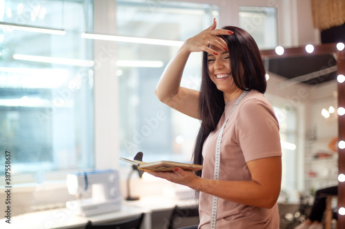 Beautiful young woman is smiling and learning to take notes of clothing measurements on sewing class Free Download Beautiful young woman is smiling and learning to take notes of clothing measurements on sewing class - GFXLoad