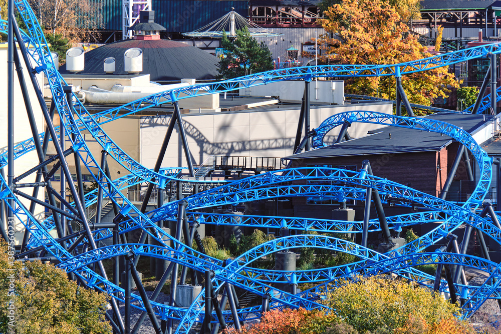 The close-up of the blue roller coaster in autumn sunny day.