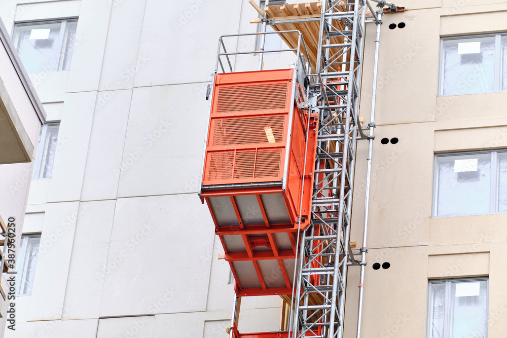 The red construction elevator on the facade of the under-construction apartment building, Espoo, Finland.