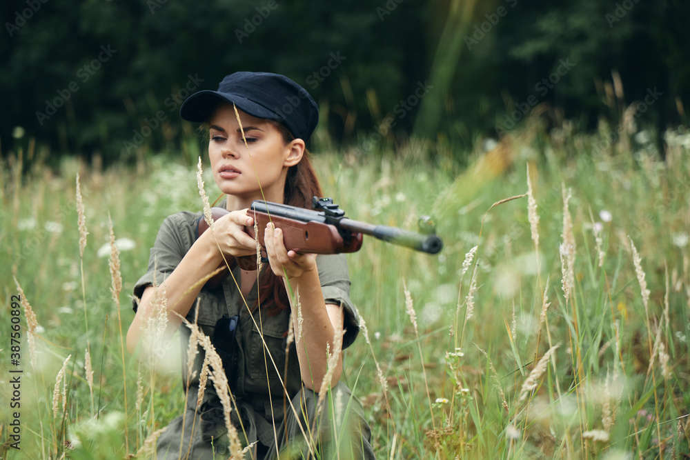 Fototapeta premium Woman on outdoor With closed eyes, weapons in hand, aiming green overalls 