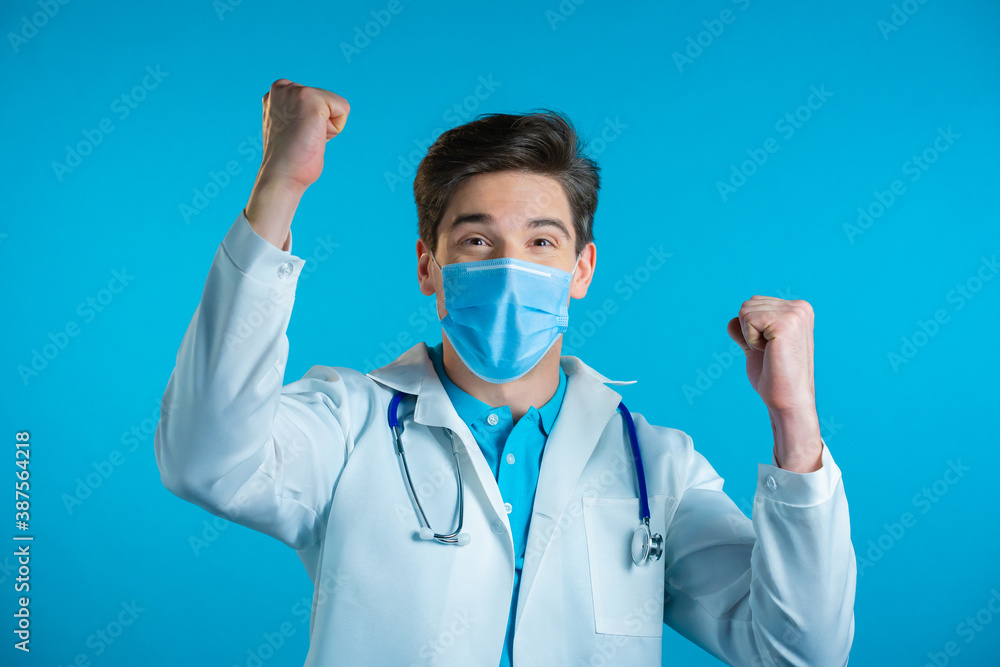 Yes winner gesture. Amazed doctor in white professional coat shocked. Handsome man surprised to camera over blue background Yes winner gesture. Amazed doctor in white professional coat shocked. Handsome man surprised to camera over blue background