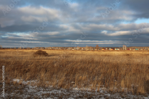 field with dry grass in winter in snow frosts in autumn