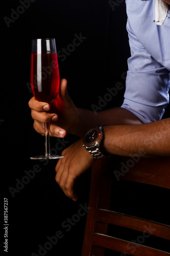 A glass of red wine with a fireplace. Hand holding glass.