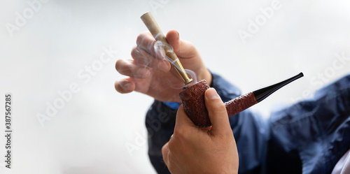 close up man burning his pipe on isolated background.