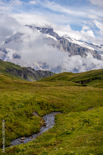 Stream in a field with Jungfrau mountain in the background on a summer day in the Valais Alps of Switzerland. 