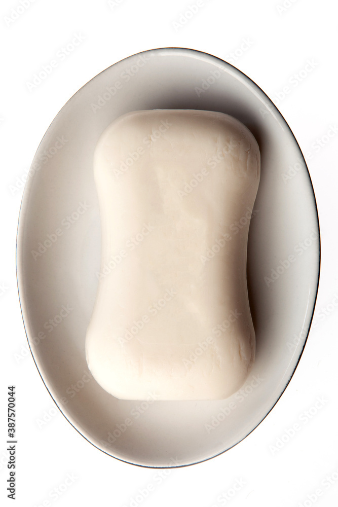 A bar of natural white soap in a soap plate isolated on white background. Studio shot. Hygiene theme - bacteria and virus prevention A bar of natural white soap in a soap plate isolated on white background. Studio shot. Hygiene theme - bacteria and virus prevention