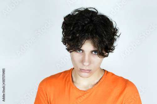 Handsome ambitious teenager on a light background, the guy is a little angry because he has to study remotely at home instead of communicating and studying in college because quarantine © Мар'ян Філь