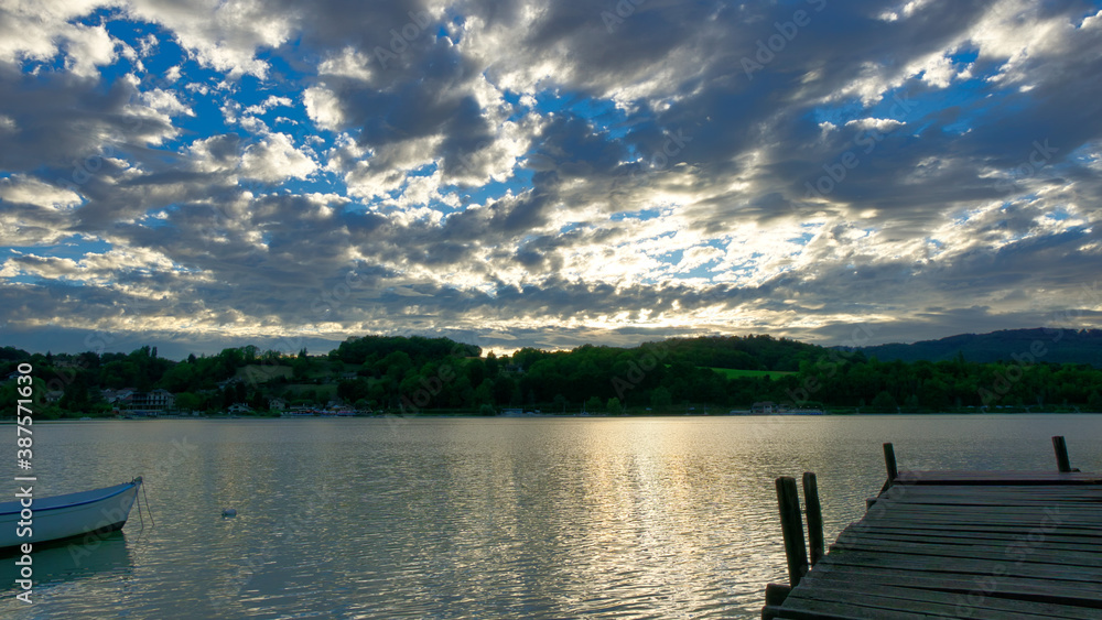 Sunset on a lake with clouds, boat and pontoon