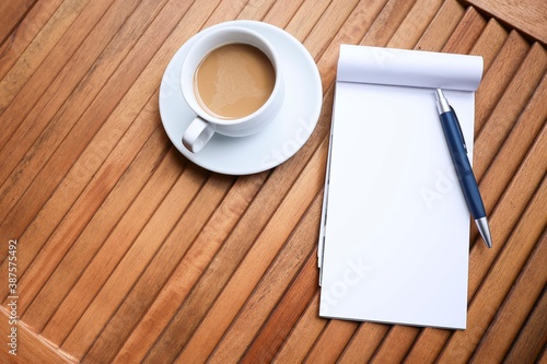 A cup of coffee and a pen on the notebook