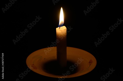 Lonely candle on a black background. A candle flame burns in the dark.