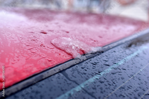 The surface and glass of the red car covered with raindrops