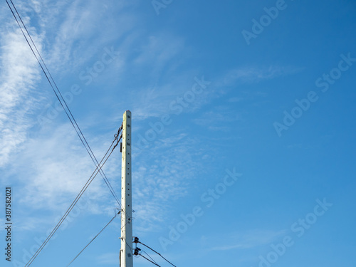 Electric poles and wires in a bright blue sky background. © Thawatchai Images
