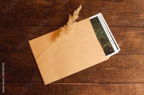 photos are enclosed in a beige envelope, located on a brown wooden table photo