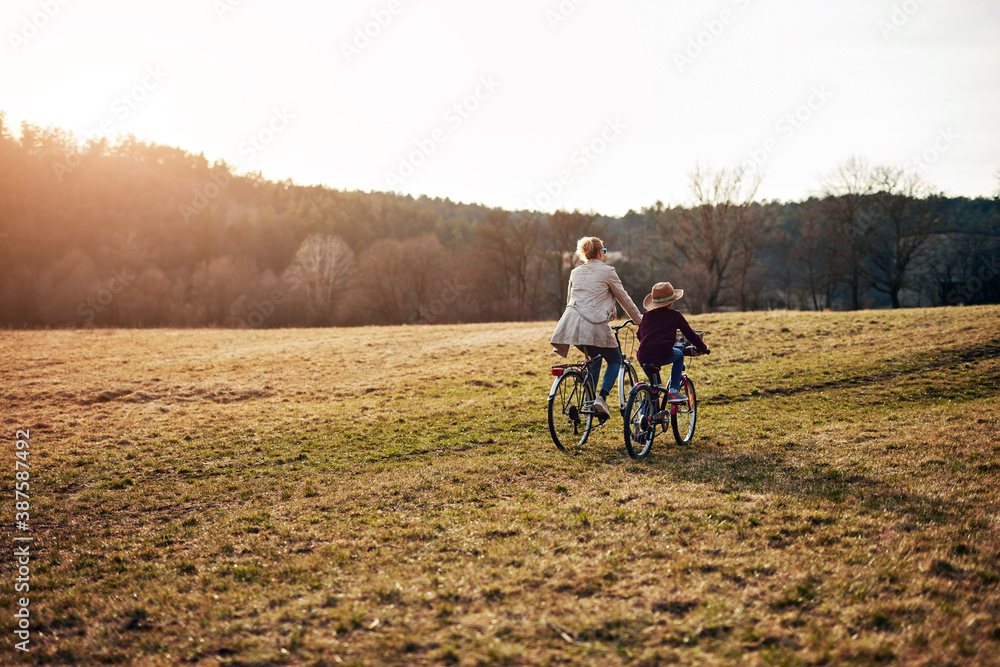 Mother and daughter riding bicycle on a countryside field.