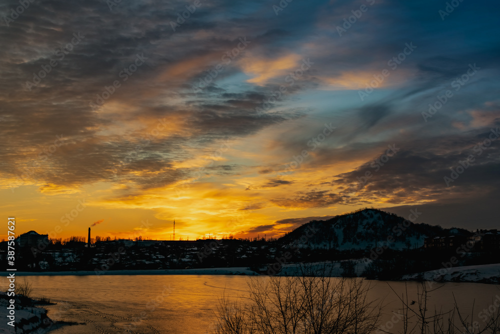 The colorful sky at sunset on a clear day plays with several colors , contrasting and rich beautiful view of the glow near the mountain and the city in winter
