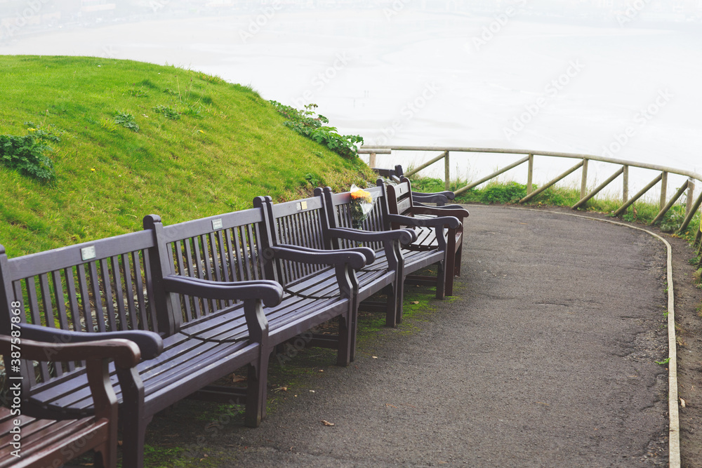 flower tribute in remembrance left on a wooden bench overlooking the sea