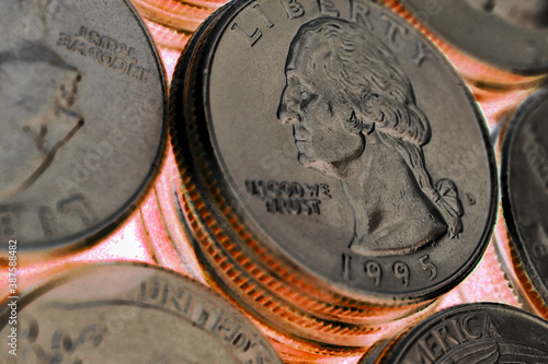 Field of American USA coins in 25 cents quarters close-up. Dark gloomy illustration about dollar, bribes, corruption and money laundering. The inverted colors. Red and golden tones. Macro