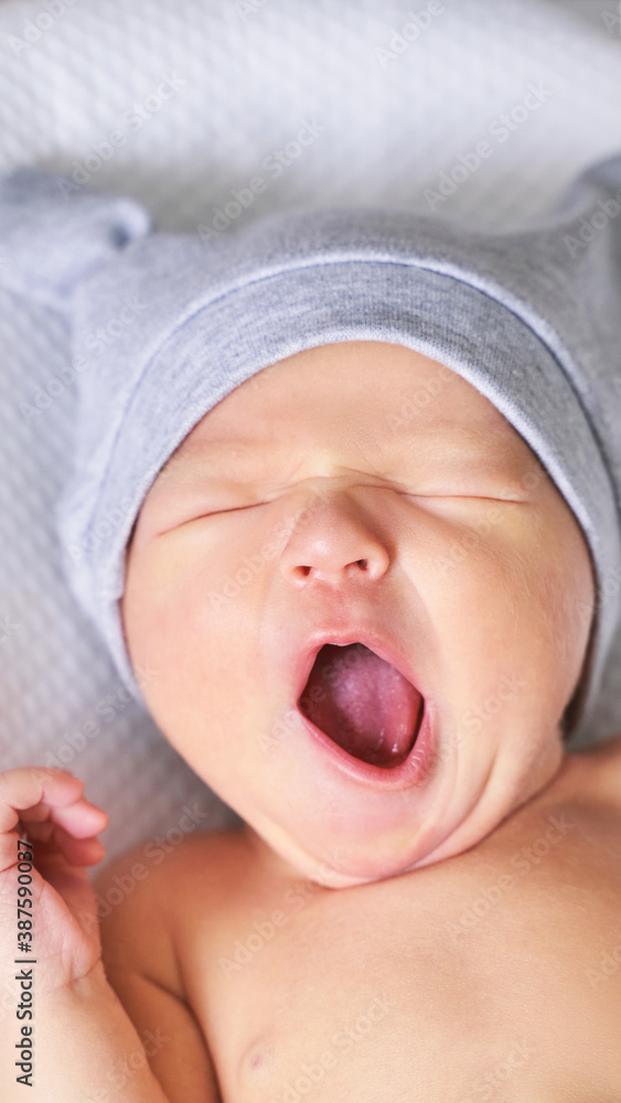 Tiny newborn in first hat. Pretty little people. Healthcare concept. Modern parenthood. Comfort and safety sleep on bed. Human insurance. Family miracle. Closed eyes and yawn Tiny newborn in first hat. Pretty little people. Healthcare concept. Modern parenthood. Comfort and safety sleep on bed. Human insurance. Family miracle. Closed eyes and yawn