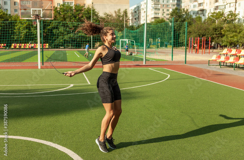 Fit woman in sportswear jumping rope outdoors