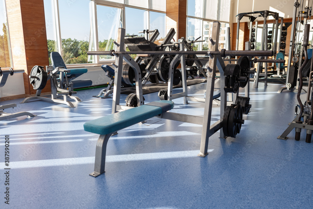 Interior of modern gym fitness room with sports and fitness equipment against the big windows
