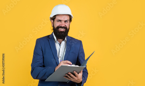working on project. building concept. builder or engineer in hard hat. happy mature architect in helmet making notes. brutal bearded man work on construction site with documents