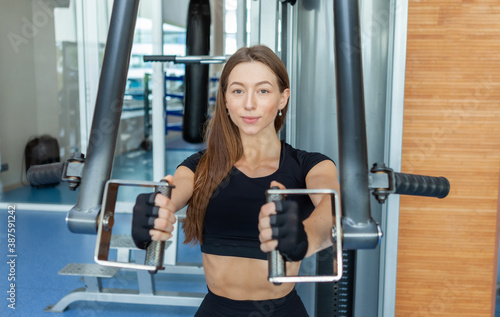 Young fit woman working out at the gym on peck deck machine. Chest and Shoulders Workout