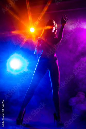 Beautiful slim sexy dancer girl wearing lingerie and high heels posing in the rays of light in a colorful smoke. Artistic, conceptual, silhouette,commercial and advertising design