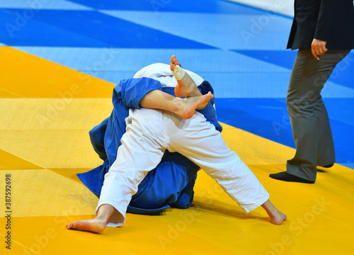 Two Girls judoka in kimono compete on the tatami 