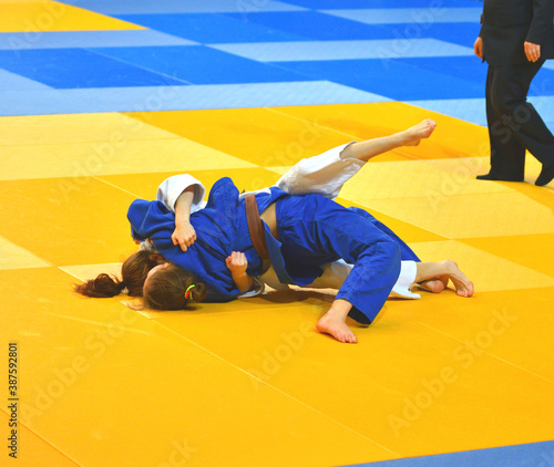Two Girls judoka in kimono compete on the tatami 