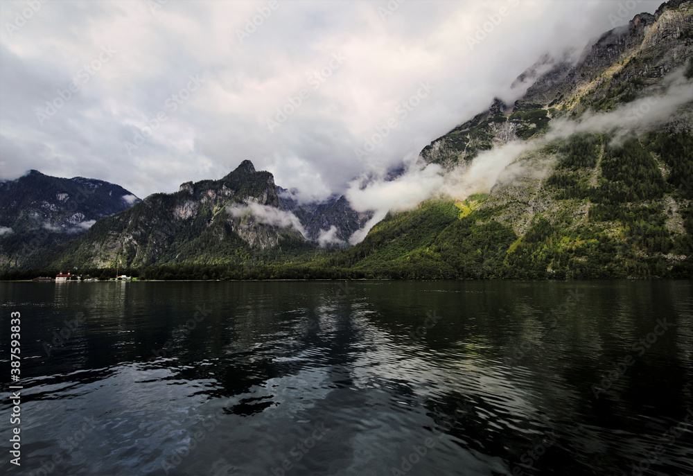 Scenic view of the Königssee and mountains surrounded by clouds in the Nationalpark Berchtesgaden, Germany shot with a wide-angle lens Scenic view of the Königssee and mountains surrounded by clouds in the Nationalpark Berchtesgaden, Germany shot with a wide-angle lens