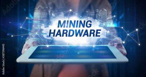 Young business person working on tablet and shows the inscription: MINING HARDWARE