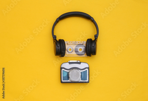 Mini audio player with stereo headphones on yellow background. Top view
