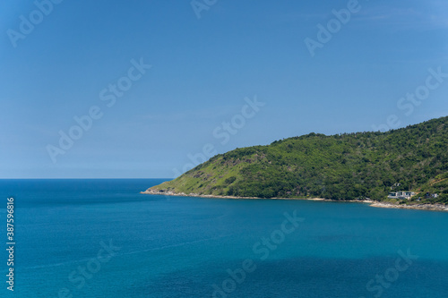 The seascape part of the island with the deep blue ocean and clear sky with the cliff full of forest tropical palm trees in the middle of summer holiday, famous tourist destination Phuket Thailand