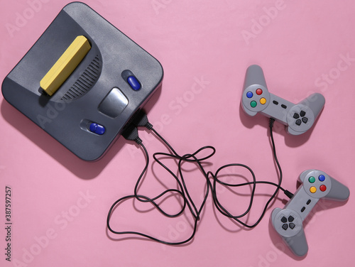 Foto Retro video game console with joysticks on pink background