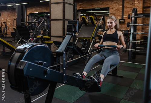 Athletic woman training on the rowing machine in gym