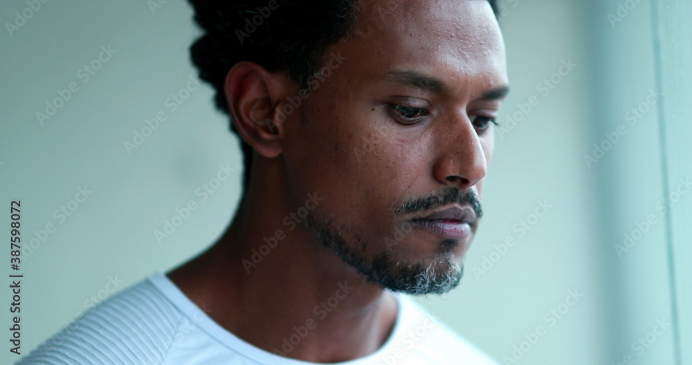 Pensive black man looking out home window.j Pensive black man looking out home window.j