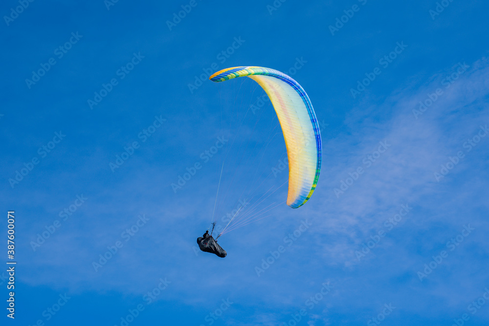 Colourful paraglider flies on a blue sky background. Extreme sport. Colourful paraglider flies on a blue sky background. Extreme sport.