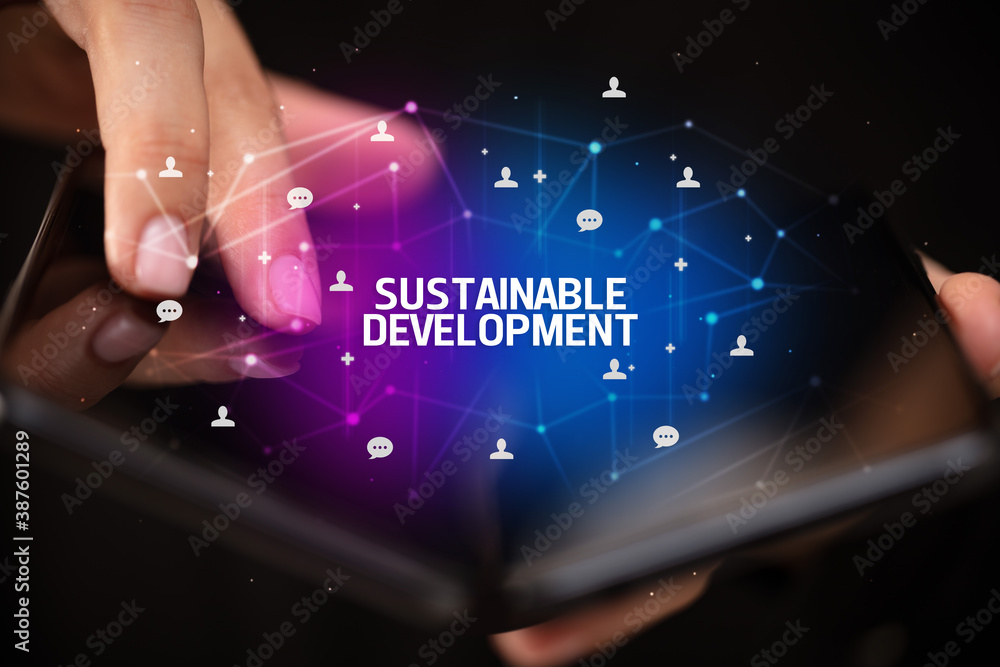 Businessman holding a foldable smartphone with SUSTAINABLE DEVELOPMENT inscription, new technology concept