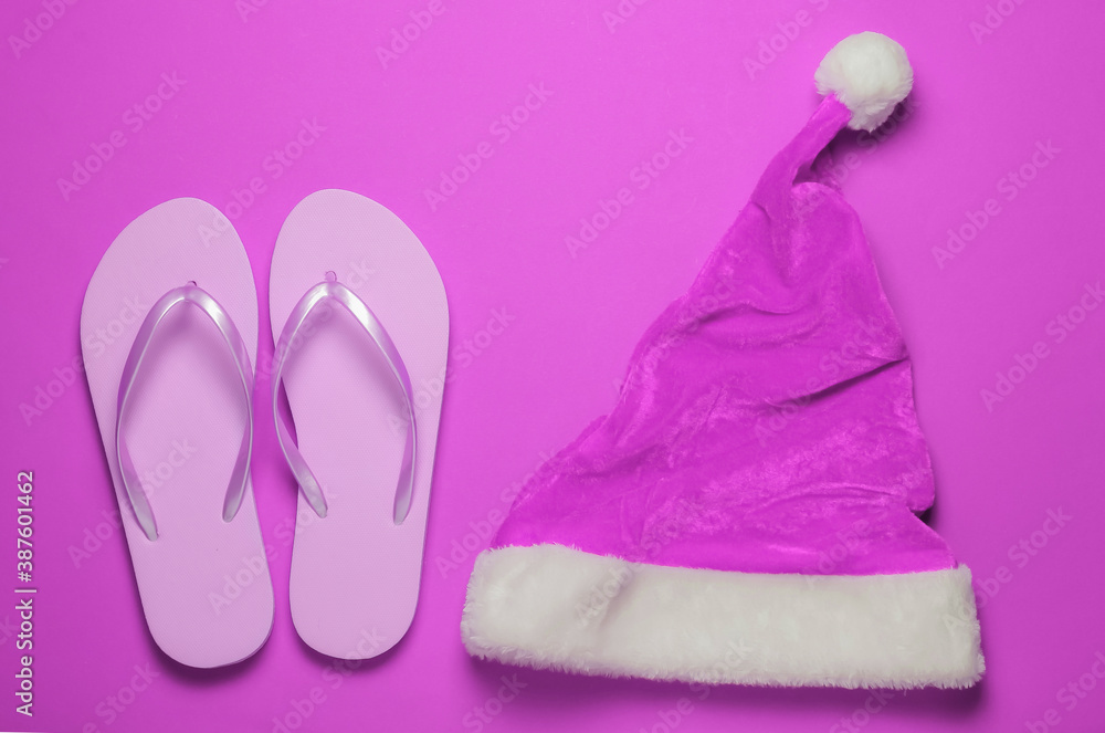 Santa hat, flip flops on pink background. New Year, Christmas holiday in warm sunny places. Beach vacation. Travel concept. Top view