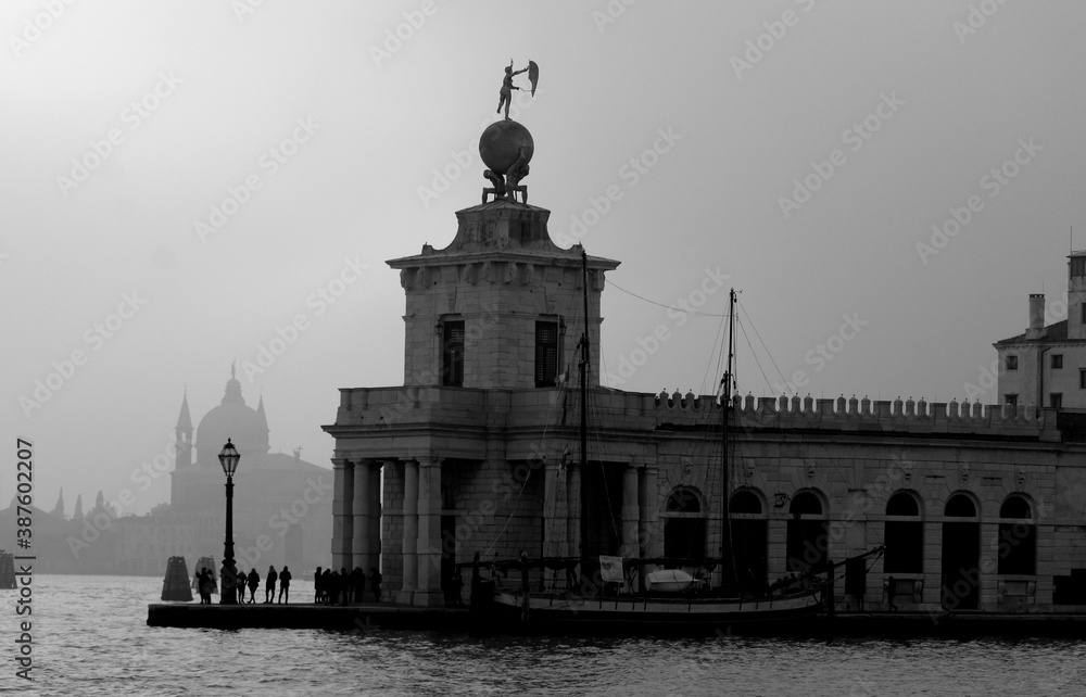 Venice, Italy, December 28, 2018 evocative black and white image of a ferry moving in a canal with basilica in the background
