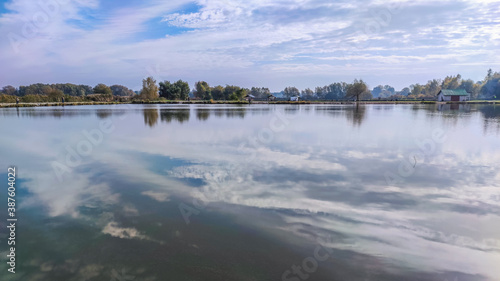 Sunny day on the perfect lake. Autumn lake with reflection on the water. Cloudy sky in the sunny day.