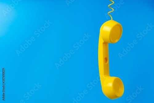 Yellow retro telephone receiver on blue background.