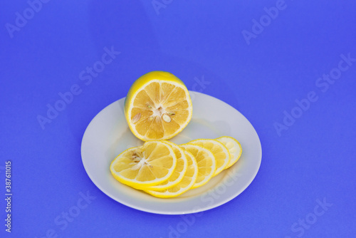 Sliced yellow lemon lies on a white plate.