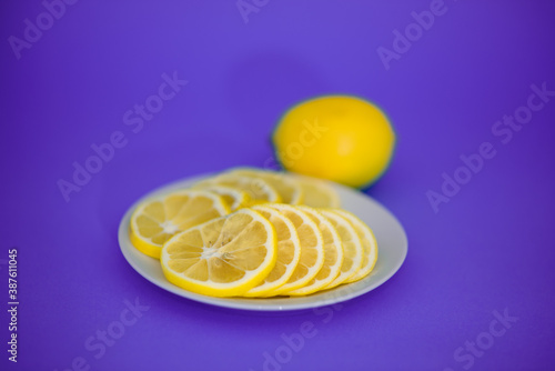 Sliced yellow lemon lies on a white plate.