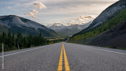 Road to the rocky mountains at sunset. Yellow road paint lines wallpaper. Empty deserted street in the countryside rural Alberta valley wallpaper